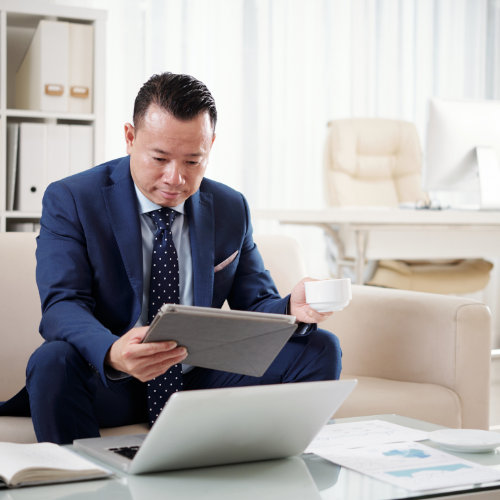 Business professional reviewing compliance documents on laptop in modern office