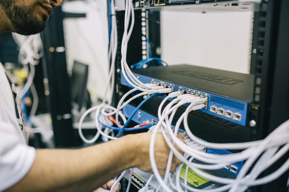 technician connecting network cables to a server rack representing sharepoint on-premises hardware infrastructure